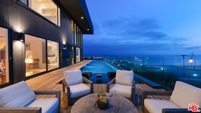 balcony at dusk featuring a water view and an outdoor living space