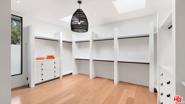 walk in closet with a skylight and light hardwood / wood-style flooring