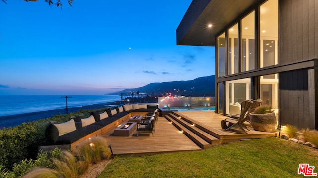 exterior space featuring a water and mountain view, a swimming pool, outdoor lounge area, and a lawn