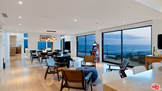 living room featuring an inviting chandelier, light hardwood / wood-style flooring, and expansive windows