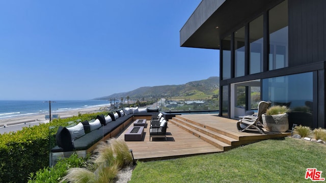 wooden terrace featuring an outdoor hangout area, a water and mountain view, a beach view, and a yard