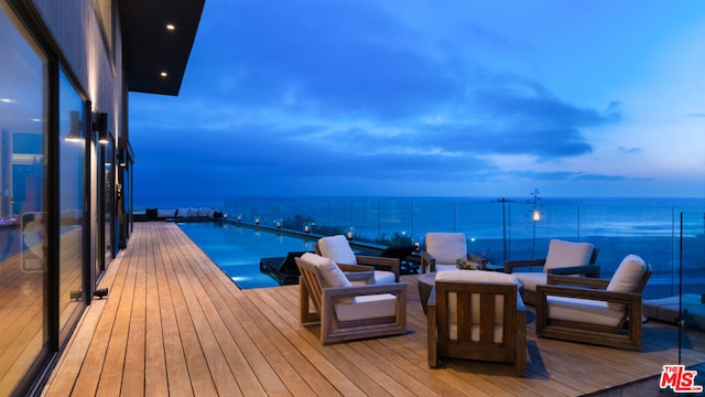 deck at dusk featuring a water view