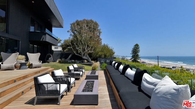 view of patio with an outdoor living space with a fire pit, a view of the beach, and a deck with water view