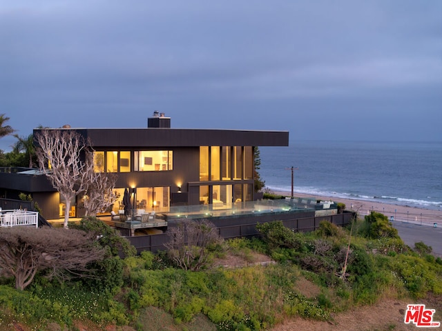 back of property featuring a water view and a view of the beach