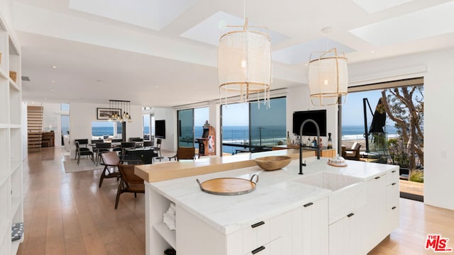 kitchen with white cabinetry, pendant lighting, a kitchen island with sink, and a notable chandelier