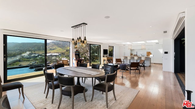 dining space featuring a mountain view, light hardwood / wood-style flooring, and an inviting chandelier