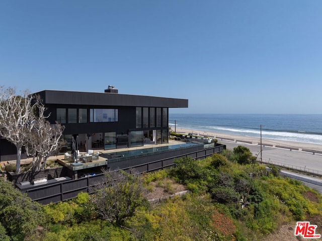 rear view of property featuring a water view and a beach view