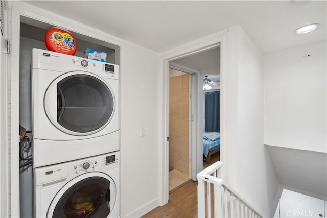 laundry area with light wood-type flooring and stacked washer / drying machine