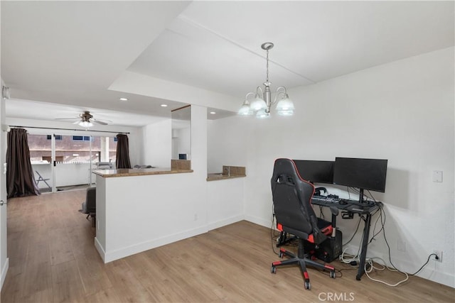 office area with light hardwood / wood-style floors and ceiling fan with notable chandelier