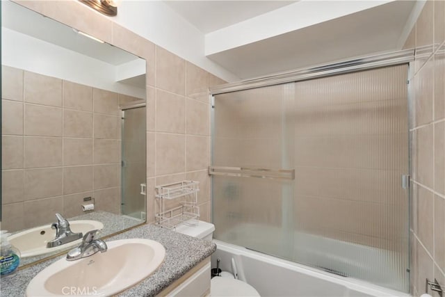 full bathroom with tile walls, toilet, vanity, and combined bath / shower with glass door