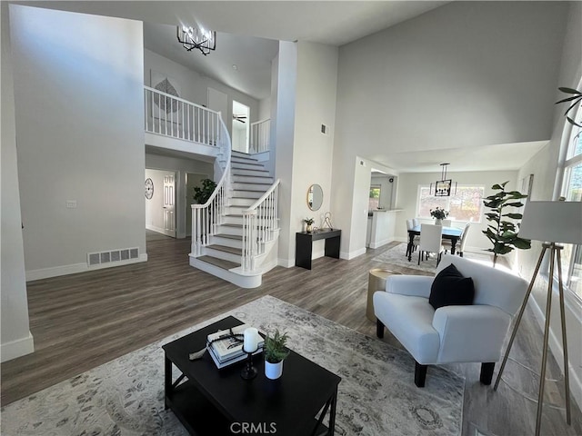 living room with a towering ceiling, an inviting chandelier, and hardwood / wood-style floors