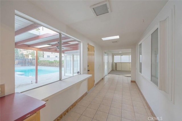 corridor featuring light tile patterned floors, a skylight, and a wealth of natural light