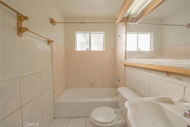 bathroom featuring tile walls, toilet, tiled shower / bath, and tile patterned flooring