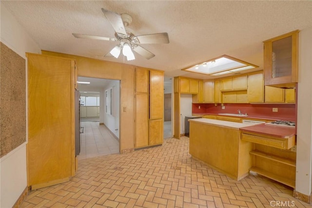 kitchen featuring ceiling fan, kitchen peninsula, sink, gas stovetop, and a textured ceiling