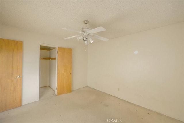 unfurnished bedroom with ceiling fan, a textured ceiling, light carpet, a walk in closet, and a closet