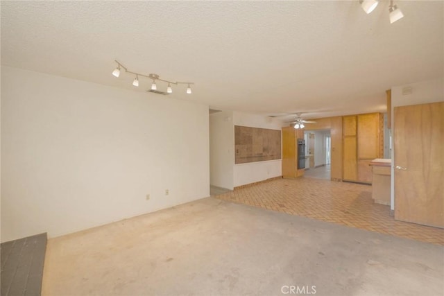 empty room with ceiling fan, light carpet, and a textured ceiling