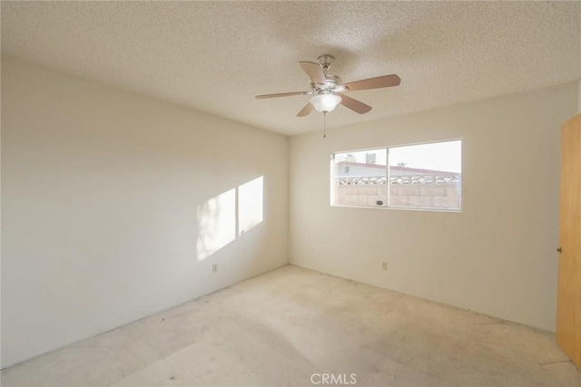 empty room with ceiling fan, a textured ceiling, and light carpet