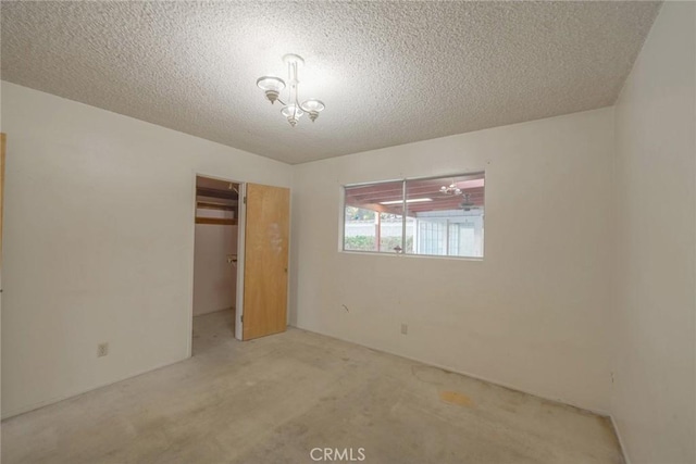 unfurnished bedroom featuring carpet floors, a textured ceiling, a closet, and a notable chandelier