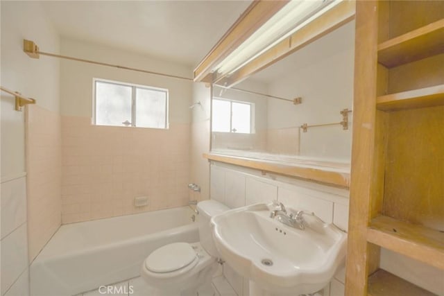 full bathroom with sink, tiled shower / bath combo, and toilet