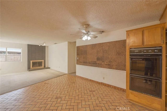 unfurnished living room with ceiling fan and a textured ceiling