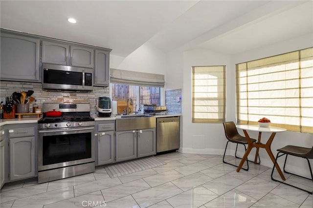 kitchen featuring vaulted ceiling, stainless steel appliances, tasteful backsplash, and gray cabinets