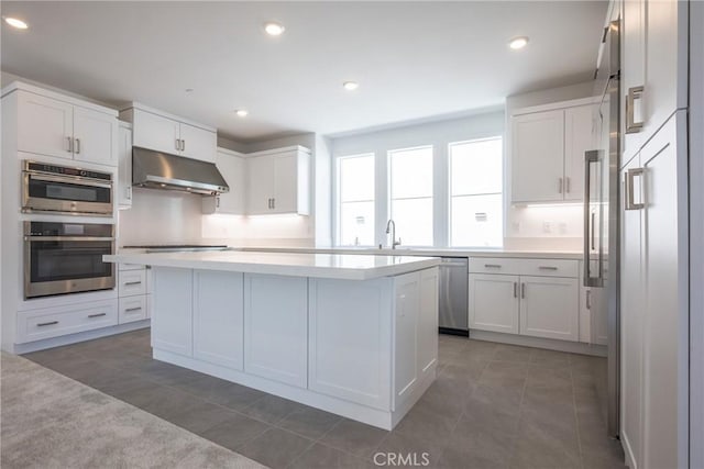 kitchen with appliances with stainless steel finishes, white cabinetry, a kitchen island, and dark tile patterned floors