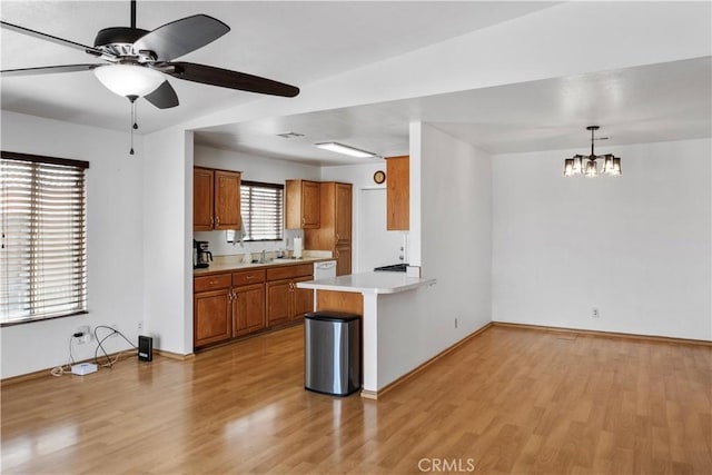 kitchen with sink, light hardwood / wood-style flooring, pendant lighting, and kitchen peninsula