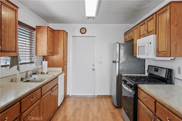 kitchen featuring sink, white appliances, and light hardwood / wood-style flooring