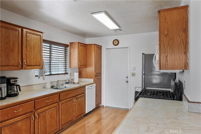 kitchen with dishwasher, sink, light hardwood / wood-style flooring, and stove