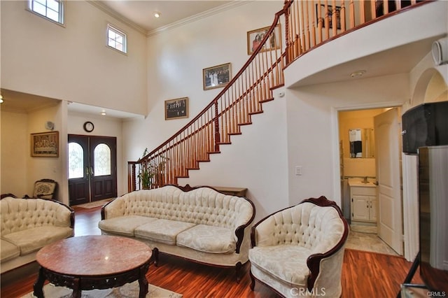 entrance foyer featuring hardwood / wood-style flooring, a high ceiling, ornamental molding, and french doors