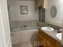 bathroom with vanity and a relaxing tiled tub