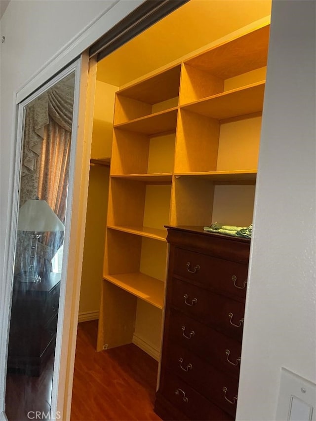 walk in closet with dark wood-type flooring