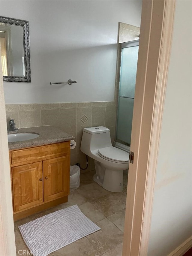 bathroom with tile walls, an enclosed shower, vanity, and toilet