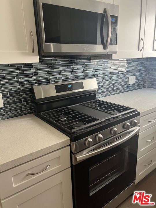 kitchen with decorative backsplash, white cabinetry, and stainless steel appliances