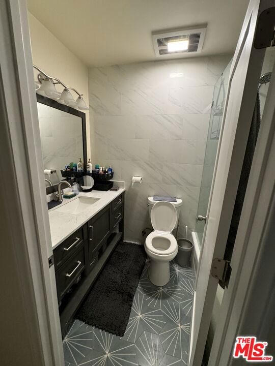 bathroom featuring tile walls, toilet, and vanity