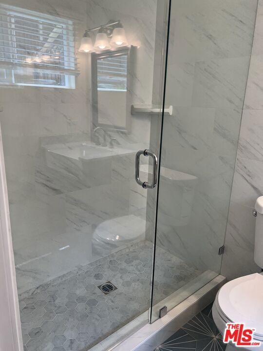 bathroom with toilet and a shower with door