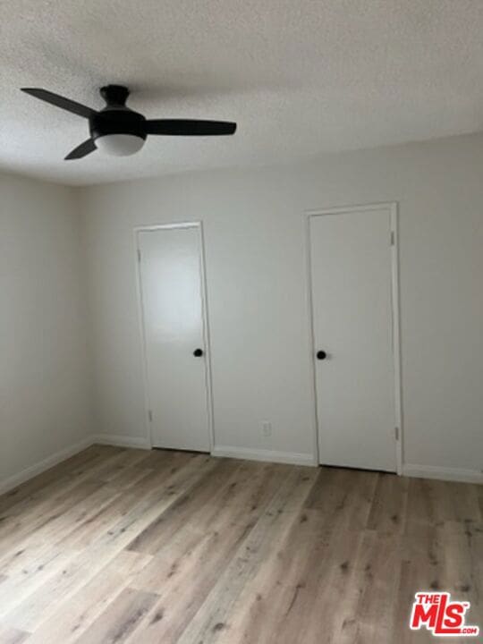 unfurnished room with ceiling fan, a textured ceiling, and light hardwood / wood-style floors