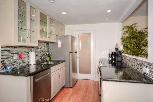 kitchen featuring appliances with stainless steel finishes, light hardwood / wood-style flooring, backsplash, and sink