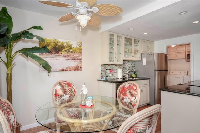 dining space featuring ceiling fan, sink, light hardwood / wood-style flooring, and washing machine and clothes dryer