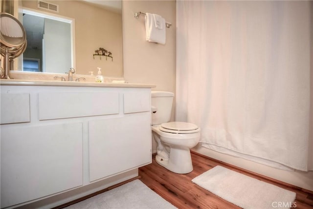 full bathroom with toilet, hardwood / wood-style flooring, vanity, and shower / bath combo with shower curtain