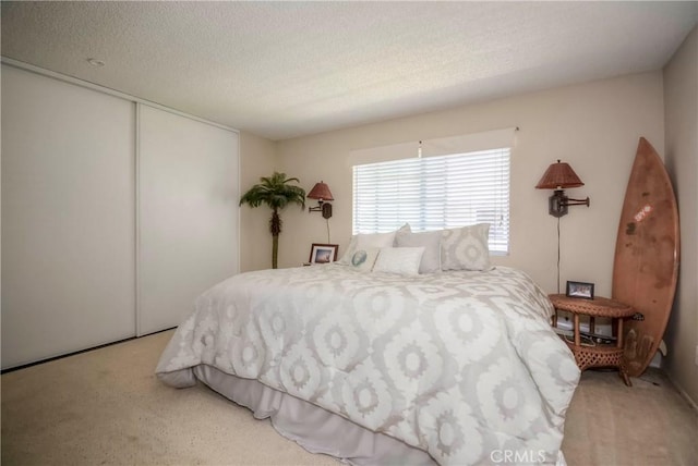 bedroom with a textured ceiling, a closet, and light colored carpet