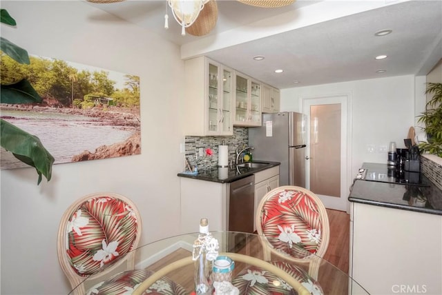 kitchen with white cabinets, stainless steel appliances, tasteful backsplash, sink, and hardwood / wood-style flooring