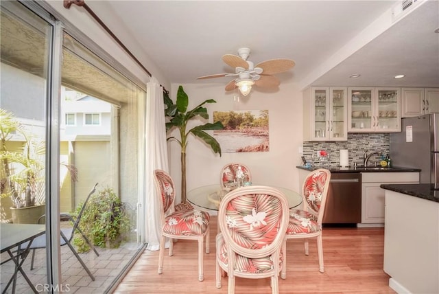 dining room featuring ceiling fan, light wood-type flooring, and sink