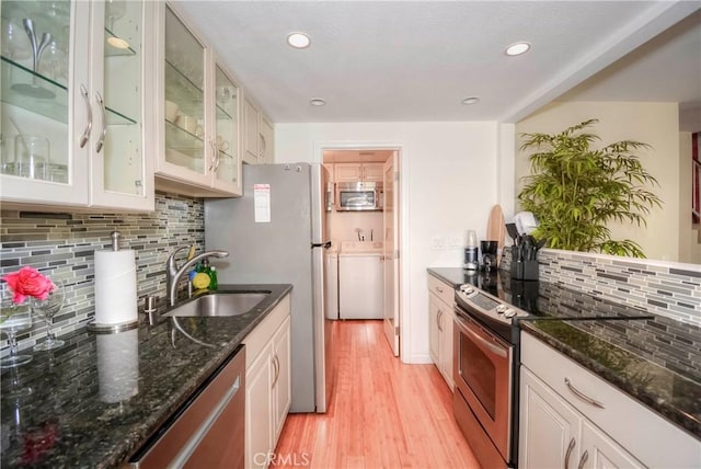 kitchen with sink, backsplash, appliances with stainless steel finishes, and dark stone countertops