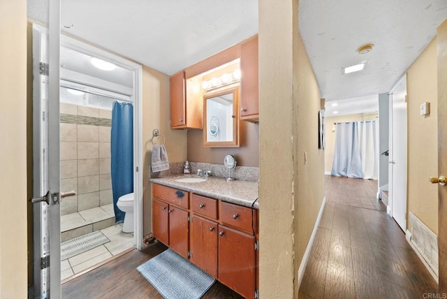 bathroom with hardwood / wood-style flooring, curtained shower, toilet, and vanity