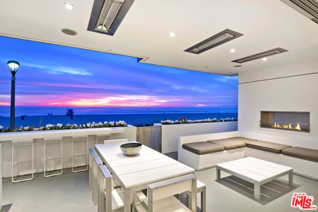 patio terrace at dusk with exterior fireplace and a water view