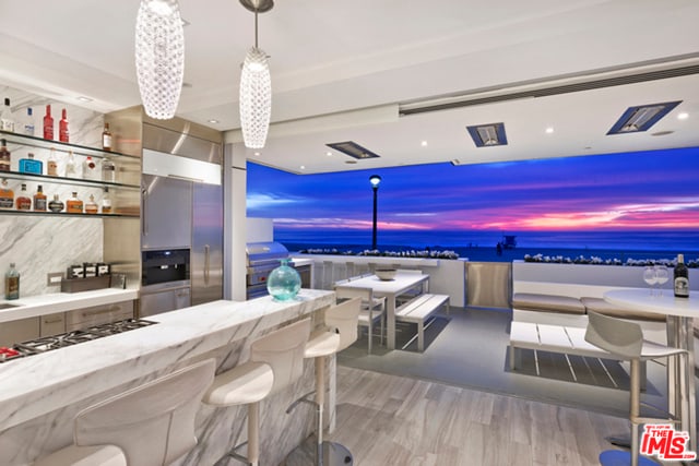 interior space with light hardwood / wood-style flooring, a kitchen bar, hanging light fixtures, a water view, and stainless steel gas stovetop