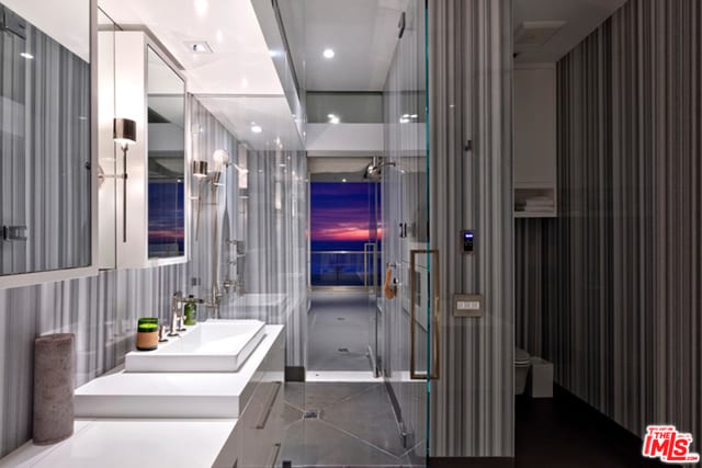 bathroom with a shower with door, tile patterned floors, toilet, and vanity