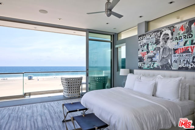 bedroom with a view of the beach, a water view, wood-type flooring, and ceiling fan