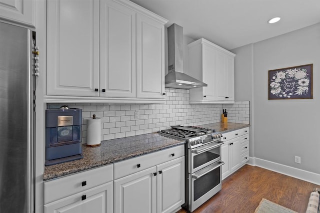 kitchen with stainless steel appliances, white cabinetry, and wall chimney range hood